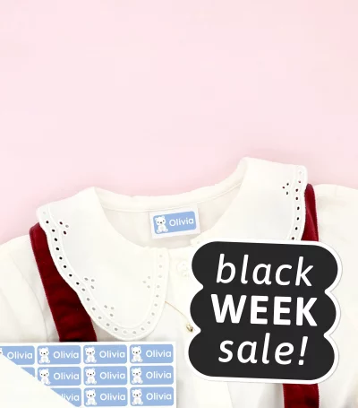 Kinderschuhe und Kinderkleid mit Namensaufklebern auf der Kleidung, umgeben von Schneeflocken-Deko. Black Week
