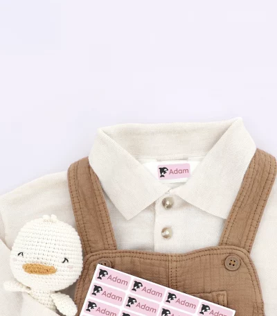 Braunes Baby-Outfit mit personalisierten Namensetiketten Adam auf Schuh und Hemd. Perfekt für individuelle Kennzeichnung von Kinderkleidung.