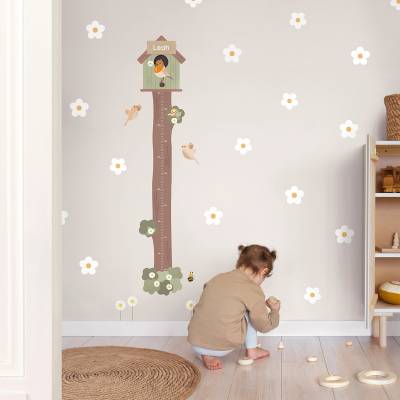 Kleinkind spielt im Kinderzimmer neben einer dekorativen Wandmesslatte mit Vogelmotiv und personalisiertem Namen. Wanddekoration für Kinderzimmer, ideal zur Raumgestaltung.