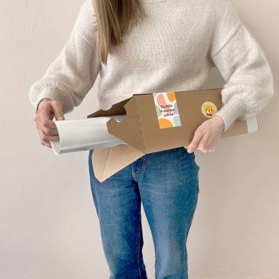 Eine Person hält eine Versandrolle mit herausragendem Poster, ideales Geschenk für das Kinderzimmer, verfügbar auf unserer Webseite für Wanddeko und personalisierte Kinderplakate.
