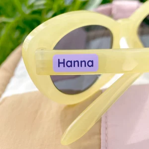 Personalisierte Namensetiketten auf gelben Sonnenbrillen, ideal für Kinder. Perfekte Ergänzung für personalisierte Produkte wie Wanddekor, Kinderzimmerplakate und Geburtstagskarten.
