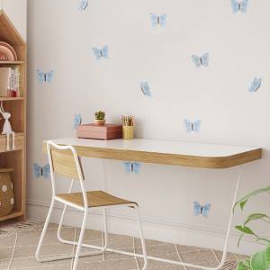 Helles Kinderzimmer mit blauen Schmetterlingen als Wanddeko, einem modernen Holzschreibtisch und einem weißen Stuhl.