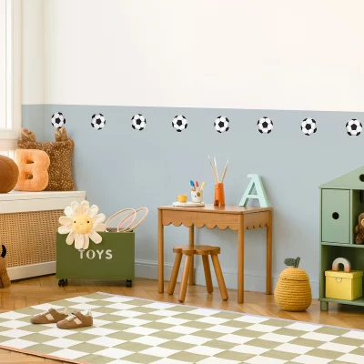 Ein kindliches Zimmer mit einer sanften Farbgestaltung, dekoriert mit Fußballs-Vinylstickern an der Wand.