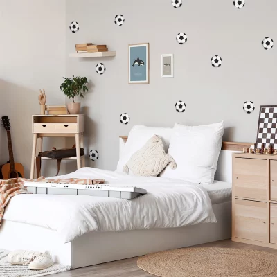 Das Bild zeigt ein stilvolles Kinderzimmer mit einer modern gestalteten Wanddekoration in Form von Fußballmotiven.
