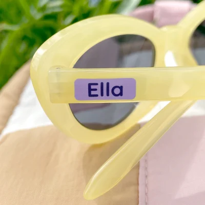 Persönliches Namensetikett auf gelben Sonnenbrillen, ideal für Kinder. Die Aufkleber sind perfekt für die Individualisierung von Accessoires und Spielzeug. Entdecken Sie passende Namenslabel und weitere Produkte für Kinderzimmerdekoration und Geburtstagskarten.