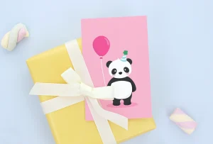 Bunte Geburtstagskarte mit einem fröhlichen Panda, der einen Ballon hält. Die Karte liegt auf einem gelben Geschenk mit einer weißen Schleife und ist ideal für Kindergeburtstage. Perfekt als Ergänzung zu unseren personalisierten Namensetiketten, Kinderzimmer-Dekoren und Plakaten.