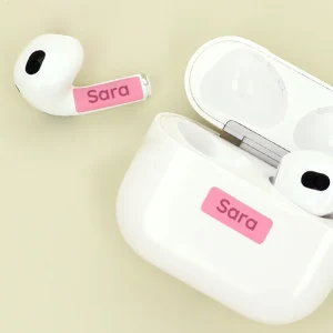 Personalisierte AirPods mit Namensaufkleber in Rosa auf der Ladehülle und einem Ohrhörer. Perfekt für Kinderzimmer, um persönliche Gegenstände identifizierbar zu machen. Ideal für Namensetiketten und kreative Wohnideen.